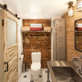 Foto di un bagno di servizio industriale con top in acciaio inossidabile, WC a due pezzi, pavimento con piastrelle a mosaico, lavabo integrato e pistrelle in bianco e nero