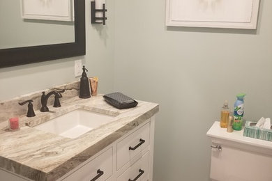 Small trendy ceramic tile and white floor powder room photo in New York with flat-panel cabinets, white cabinets, a two-piece toilet, green walls, a drop-in sink, laminate countertops and beige countertops