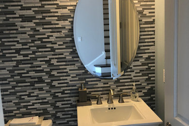 Inspiration för små moderna vitt toaletter, med en toalettstol med separat cisternkåpa, svart och vit kakel, stickkakel, grå väggar, mörkt trägolv, ett piedestal handfat, bänkskiva i akrylsten och brunt golv