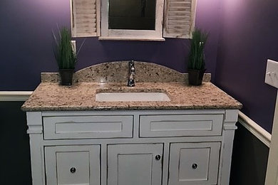 Small farmhouse dark wood floor powder room photo in Other with purple walls, an undermount sink, furniture-like cabinets, yellow cabinets and granite countertops
