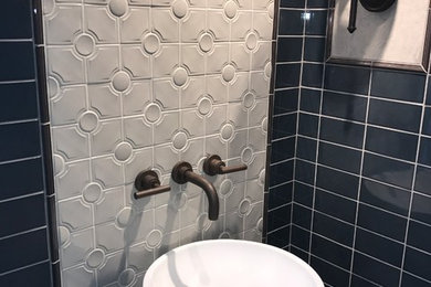 ロサンゼルスにあるトランジショナルスタイルのおしゃれなトイレ・洗面所 (黒いタイル、ガラスタイル、マルチカラーの壁、一体型シンク) の写真