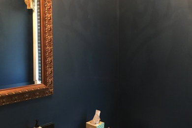 Kleine Moderne Gästetoilette mit Schrankfronten mit vertiefter Füllung, dunklen Holzschränken, Wandtoilette mit Spülkasten, blauer Wandfarbe, Unterbauwaschbecken, Mineralwerkstoff-Waschtisch und schwarzer Waschtischplatte in Cleveland