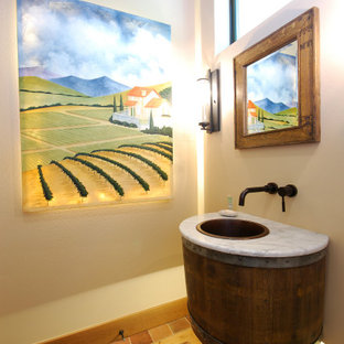 Powder room - mid-sized country brown floor powder room idea in Seattle with white walls, marble countertops, white countertops, dark wood cabinets and a drop-in sink
