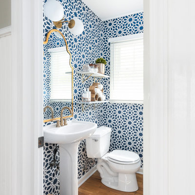 Powder room - transitional medium tone wood floor and brown floor powder room idea in Chicago with a two-piece toilet, a pedestal sink and multicolored walls