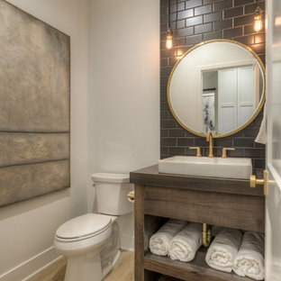 Exemple d'un WC et toilettes nature avec un placard sans porte, des portes de placard en bois sombre, un WC séparé, un carrelage gris, un carrelage marron, un carrelage métro, un mur blanc, un plan vasque, un plan de toilette en bois, un sol marron et un plan de toilette gris.