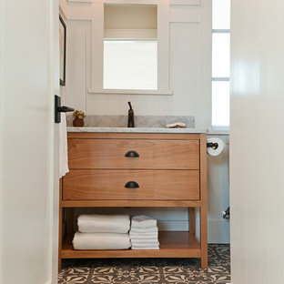Cette photo montre un petit WC et toilettes montagne avec des portes de placard en bois brun, un WC à poser, un carrelage multicolore, un mur blanc, béton au sol, un lavabo encastré, un plan de toilette en marbre et un placard à porte plane.