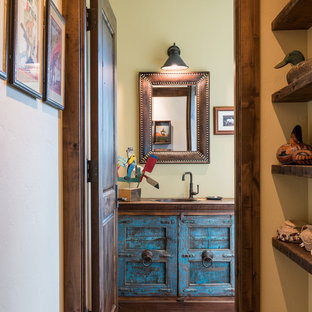 Exemple d'un WC et toilettes sud-ouest américain avec des portes de placard en bois vieilli, un sol en bois brun, un lavabo posé, un plan de toilette en bois et un plan de toilette marron.