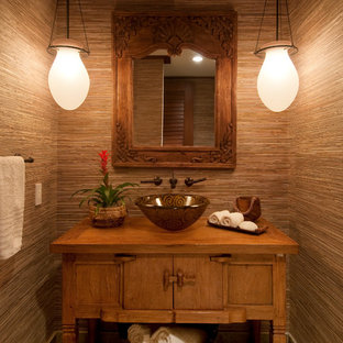 Immagine di un bagno di servizio tropicale con lavabo a bacinella, consolle stile comò, ante in legno scuro e pareti marroni