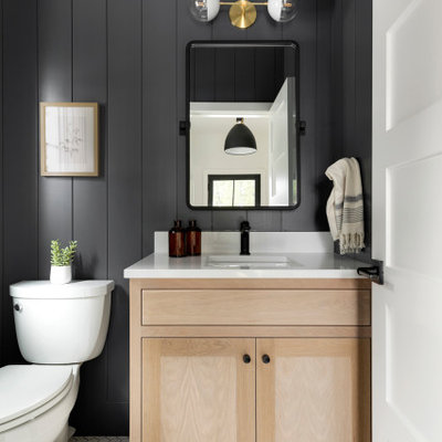 Inspiration for a transitional mosaic tile floor, white floor and shiplap wall powder room remodel in Minneapolis with shaker cabinets, light wood cabinets, a two-piece toilet, black walls, an undermount sink, white countertops and a built-in vanity