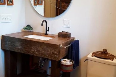 Mid-sized eclectic powder room photo in New York with open cabinets, dark wood cabinets, a one-piece toilet, white walls, an undermount sink and wood countertops