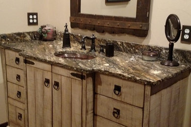 Example of a mountain style dark wood floor powder room design in Denver with furniture-like cabinets, distressed cabinets, beige walls, an undermount sink and granite countertops