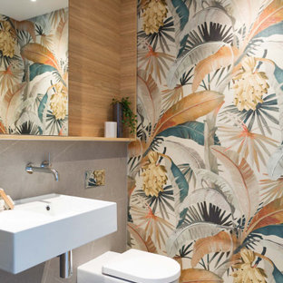 This is an example of a mid-sized contemporary powder room in Sydney with a one-piece toilet, gray tile, ceramic tile, a wall-mount sink and wallpaper.