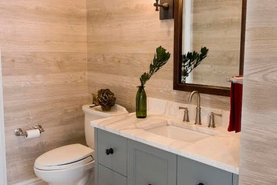 Inspiration för stora moderna toaletter, med släta luckor, grå skåp, en toalettstol med separat cisternkåpa, beige kakel, beige väggar, ett väggmonterat handfat, marmorbänkskiva, beiget golv och klinkergolv i porslin