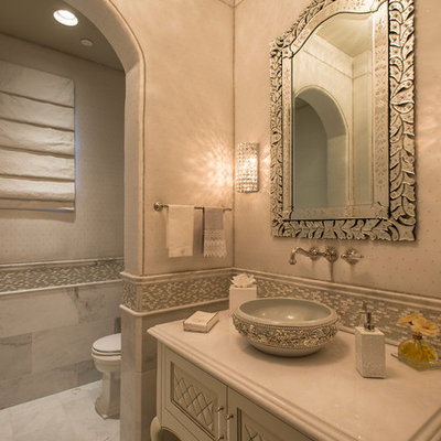 Mid-sized tuscan mosaic tile and gray tile marble floor powder room photo in Phoenix with a vessel sink, furniture-like cabinets, white cabinets, beige walls, a two-piece toilet and solid surface countertops