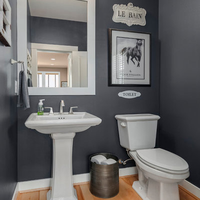 Inspiration for a mid-sized transitional light wood floor and brown floor powder room remodel in Seattle with a two-piece toilet, gray walls, a pedestal sink and solid surface countertops