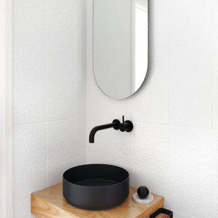 This is an example of a small contemporary powder room in Sydney with white tile, ceramic tile, white walls, a vessel sink and wood benchtops.