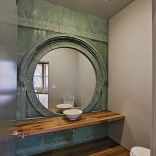Idée de décoration pour un WC et toilettes urbain de taille moyenne avec une vasque, un plan de toilette en bois, un mur vert, un sol en bois brun, un sol marron et un plan de toilette marron.