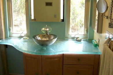 Example of a small powder room design in Chicago with glass countertops, raised-panel cabinets, medium tone wood cabinets and a vessel sink