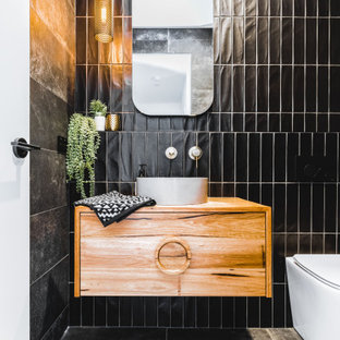 Small contemporary powder room in Sydney with black tile, flat-panel cabinets, medium wood cabinets, a one-piece toilet, a vessel sink, wood benchtops, grey floor, brown benchtops and a floating vanity.