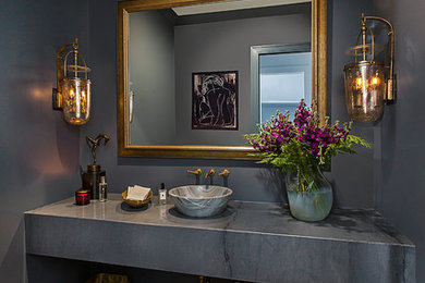 Example of a mid-sized trendy medium tone wood floor and brown floor powder room design in Detroit with gray walls, a vessel sink and gray countertops