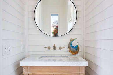 Example of a small transitional powder room design in Miami with an undermount sink, furniture-like cabinets, light wood cabinets, white walls and granite countertops