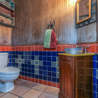Aménagement d'un grand WC et toilettes sud-ouest américain avec un WC séparé, un carrelage marron, un carrelage bleu, un carrelage orange, un carrelage multicolore, des carreaux de porcelaine, un sol en carrelage de porcelaine, un lavabo encastré, un plan de toilette en granite, des portes de placard en bois brun, un mur multicolore, un placard en trompe-l'oeil et un plan de toilette jaune.