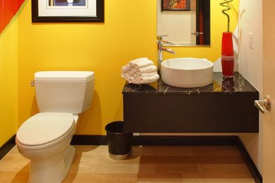 Exempel på ett mellanstort modernt svart svart toalett, med släta luckor, svarta skåp, en toalettstol med separat cisternkåpa, gul kakel, ljust trägolv, ett fristående handfat, marmorbänkskiva och gult golv