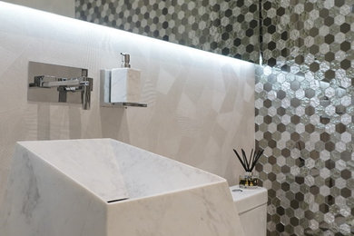 Diseño de aseo contemporáneo grande con sanitario de una pieza, baldosas y/o azulejos grises, baldosas y/o azulejos blancos, lavabo integrado y suelo beige