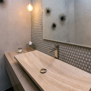 Exempel på ett mellanstort modernt beige beige toalett, med släta luckor, grå skåp, en toalettstol med hel cisternkåpa, beige kakel, glaskakel, beige väggar, mörkt trägolv, ett fristående handfat, bänkskiva i travertin och brunt golv