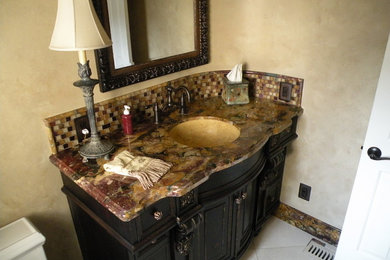 Inspiration for a mid-sized craftsman brown tile and mosaic tile powder room remodel in Charlotte with dark wood cabinets, a two-piece toilet, beige walls, an undermount sink, marble countertops and furniture-like cabinets