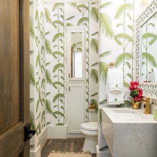 Esempio di un bagno di servizio tropicale con ante bianche, WC monopezzo, pareti multicolore, pavimento in legno massello medio, top in quarzo composito, pavimento marrone e lavabo sottopiano
