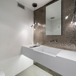 Réalisation d'un WC et toilettes design avec un lavabo intégré, un plan de toilette en quartz, carrelage en métal, un mur blanc et un plan de toilette blanc.