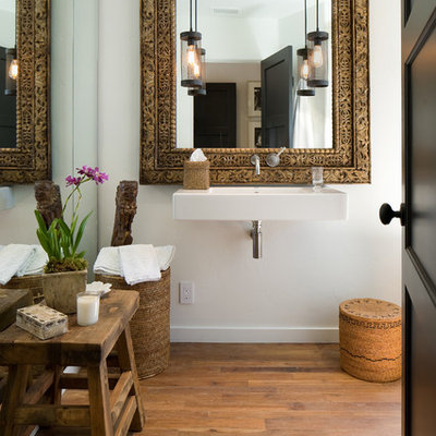 Inspiration for a mid-sized mediterranean medium tone wood floor powder room remodel in Santa Barbara with a wall-mount sink and white walls