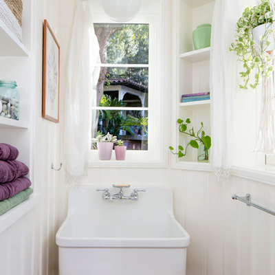 Example of a small tuscan terra-cotta tile ceramic tile and brown floor powder room design in Los Angeles with white walls, a wall-mount sink, open cabinets and white cabinets
