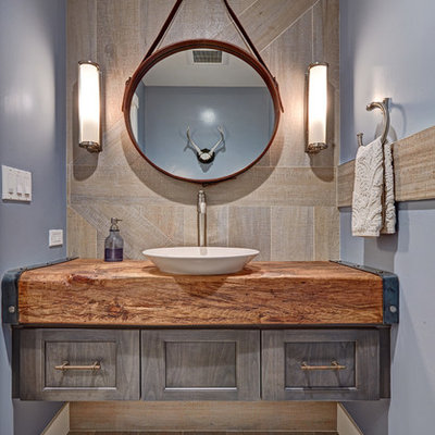 Inspiration for a small cottage gray tile and porcelain tile porcelain tile powder room remodel in Sacramento with a vessel sink, recessed-panel cabinets, gray cabinets, wood countertops, blue walls and brown countertops