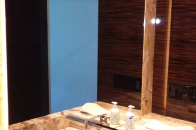 Cette photo montre un WC et toilettes moderne en bois foncé de taille moyenne avec un lavabo suspendu, un placard à porte plane, un plan de toilette en onyx, WC à poser et un mur beige.