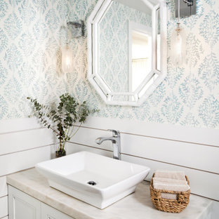 Foto på ett mellanstort maritimt beige toalett, med luckor med infälld panel, beige skåp, flerfärgade väggar och ett fristående handfat
