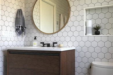 Kleine Moderne Gästetoilette mit weißer Wandfarbe, flächenbündigen Schrankfronten, dunklen Holzschränken, Toilette mit Aufsatzspülkasten, weißen Fliesen, Porzellanfliesen, dunklem Holzboden, Unterbauwaschbecken, Mineralwerkstoff-Waschtisch, braunem Boden und weißer Waschtischplatte in San Francisco