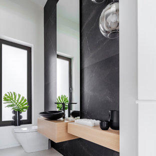 Immagine di un bagno di servizio moderno di medie dimensioni con WC monopezzo, piastrelle nere, pareti bianche, pavimento in marmo, lavabo a bacinella, top in legno, pavimento bianco e top beige