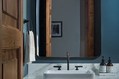 デンバーにあるトランジショナルスタイルのおしゃれなトイレ・洗面所 (シェーカースタイル扉のキャビネット、黒いキャビネット、青い壁、ベッセル式洗面器、白い洗面カウンター) の写真