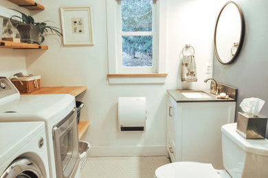 Example of a mid-sized trendy porcelain tile and gray floor powder room design with shaker cabinets, white cabinets, a two-piece toilet, blue walls, an undermount sink, quartz countertops and gray countertops