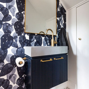 Inspiration for a contemporary powder room in Sydney with raised-panel cabinets, blue cabinets, white walls, an integrated sink, multi-coloured floor, grey benchtops, a built-in vanity, vaulted and wallpaper.