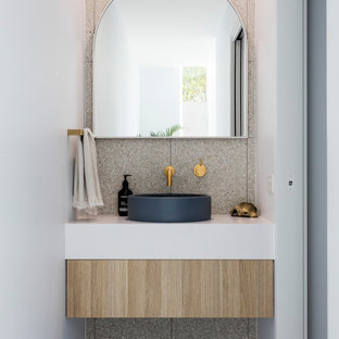 Design ideas for a contemporary powder room in Sunshine Coast with flat-panel cabinets, light wood cabinets, gray tile, white walls, a vessel sink, grey floor and white benchtops.