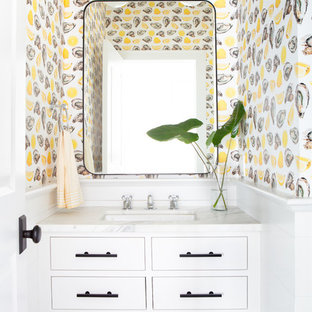 Inspiration pour un WC et toilettes marin de taille moyenne avec un placard en trompe-l'oeil, des portes de placard blanches, un mur multicolore, un lavabo encastré, un plan de toilette blanc, un WC à poser et un plan de toilette en marbre.