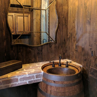 Foto di un piccolo bagno di servizio rustico con ante con bugna sagomata, ante in legno scuro, WC monopezzo, pareti marroni, pavimento in mattoni, lavabo integrato e pavimento rosso