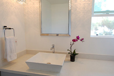 Medium sized contemporary cloakroom in Los Angeles with a vessel sink, flat-panel cabinets, grey cabinets, engineered stone worktops, a two-piece toilet, grey tiles and white walls.