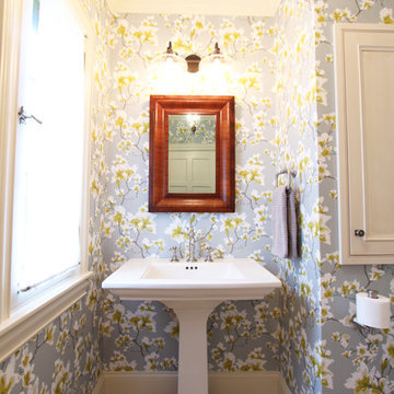 Pedestal Sink with Wood Toned Mirror Above on Wallpapered Wall