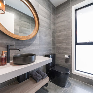 Photo of a mid-sized contemporary powder room in Gold Coast - Tweed with grey cabinets, a one-piece toilet, gray tile, a console sink and a floating vanity.