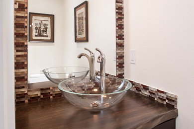 Example of a small eclectic multicolored tile powder room design in Seattle with a vessel sink, shaker cabinets, dark wood cabinets, wood countertops, white walls and brown countertops