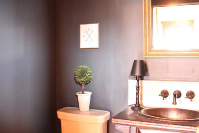 Modelo de aseo de estilo americano con lavabo encastrado, encimera de madera, baldosas y/o azulejos blancos, paredes azules y suelo de madera en tonos medios